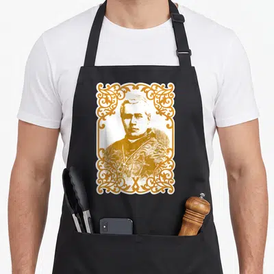 Tablier de cuisine noir avec portrait de Pape Saint Pie X encadré de motifs dorés et ornementaux complexes.