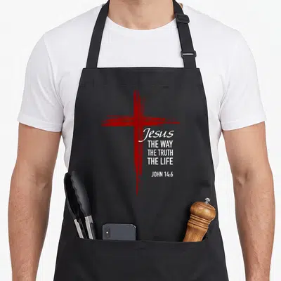 Tablier de cuisine noir avec une croix rouge stylisée et le texte Jésus The Way The Truth The Life John 14:6 en blanc.