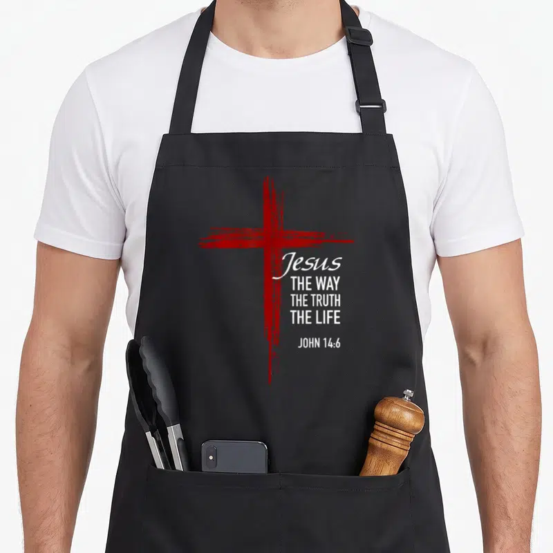 Tablier de cuisine noir avec une croix rouge stylisée et le texte Jésus The Way The Truth The Life John 14:6 en blanc.