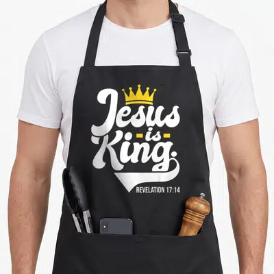 Tablier de cuisine noir avec inscription Jesus is King, couronne jaune et texte Revelation 17:14 en blanc.