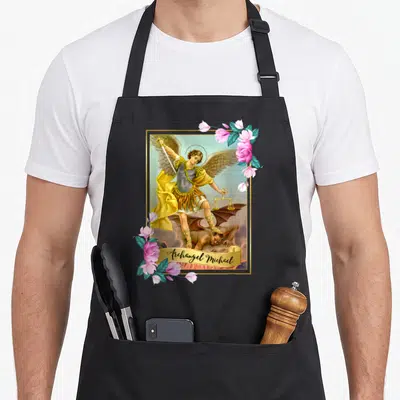 Tablier de cuisine noir avec une illustration colorée de l'Archange Michel tenant une balance et un sabre, encadré de fleurs roses.