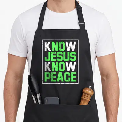 Tablier de cuisine noir avec l'inscription Know Jesus Know Peace en vert et blanc dans un cadre rectangulaire.