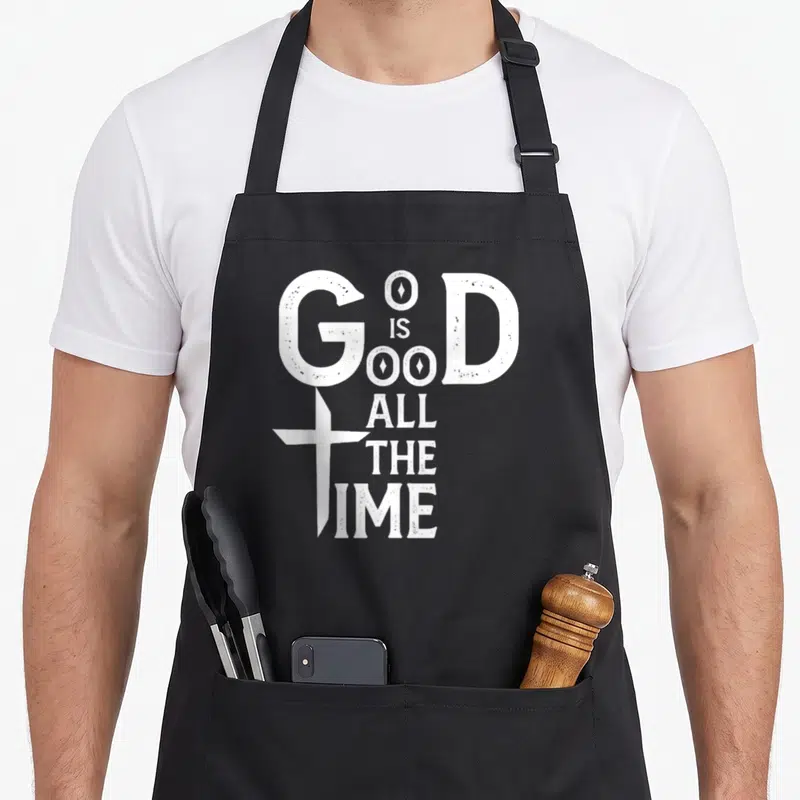 Tablier de cuisine noir avec inscription blanche « God Is Good All Time » et croix stylisée intégrée au G.