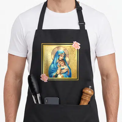 Tablier de cuisine noir avec une Sainte Vierge Marie en bleu et or, entourée de roses roses dans un cadre doré.