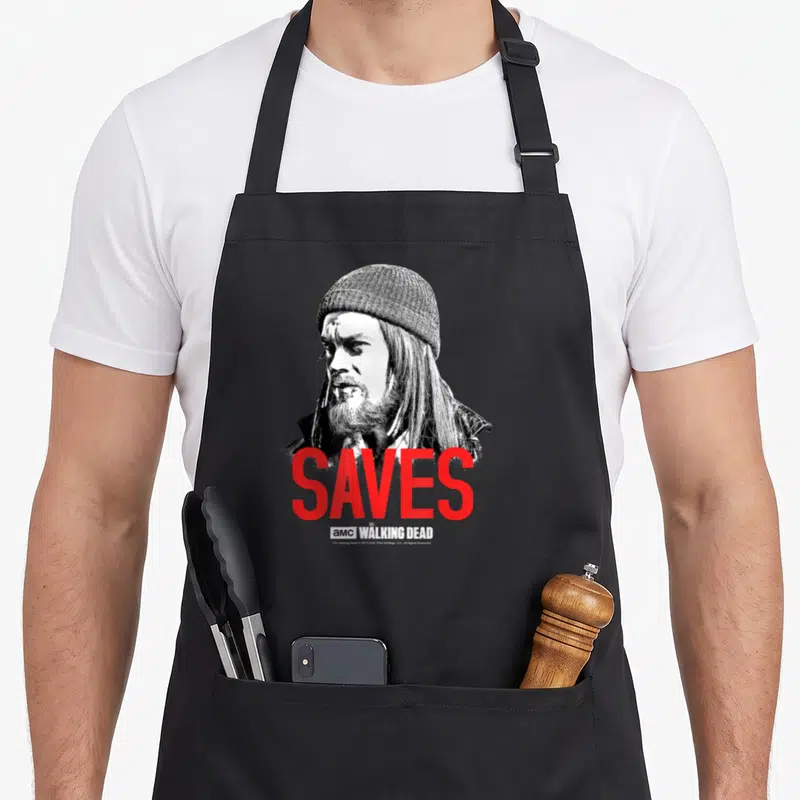 Tablier de cuisine noir avec portrait Negan et le mot SAVES en lettres rouges vives.
