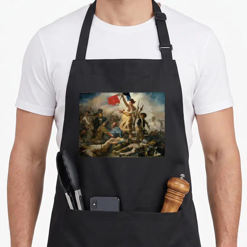 Tablier de cuisine noir avec reproduction de La liberté guidant le peuple de Delacroix imprimée sur le devant.