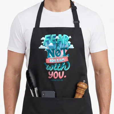 Tablier de cuisine noir avec l'inscription FEAR NOT FOR I AM with YOU et une silhouette sautant entre les lettres bleues et roses.