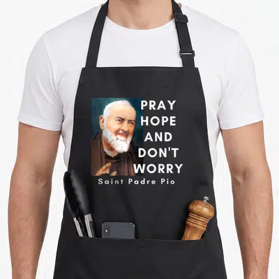 Tablier de cuisine noir avec portrait de Saint Padre Pio et texte Pray hope and don't worry en blanc.