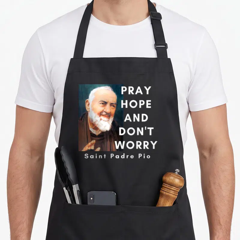 Tablier de cuisine noir avec portrait de Saint Padre Pio et texte Pray hope and don't worry en blanc.
