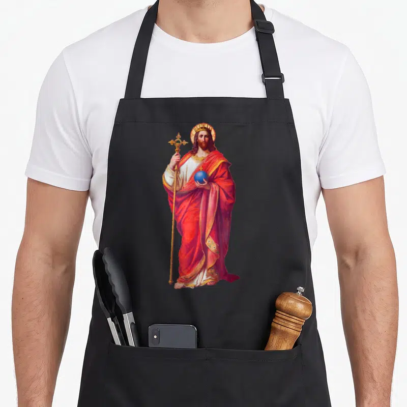 Tablier de cuisine noir avec une illustration colorée de Jésus Christ tenant un sceptre et une sphère bleue.