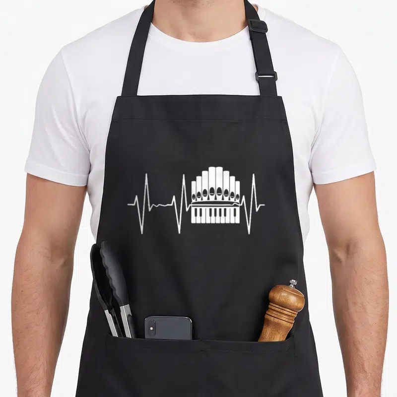 Tablier de cuisine noir avec un orgue stylisé en ligne blanche évoquant un rythme vital.