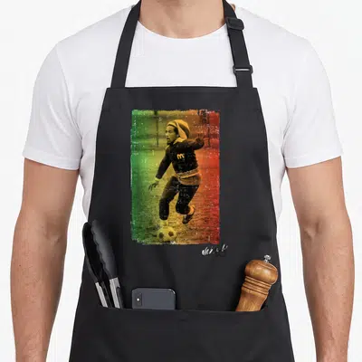 Tablier de cuisine noir avec illustration de Bob Marley jouant au football sur fond vert jaune et rouge.