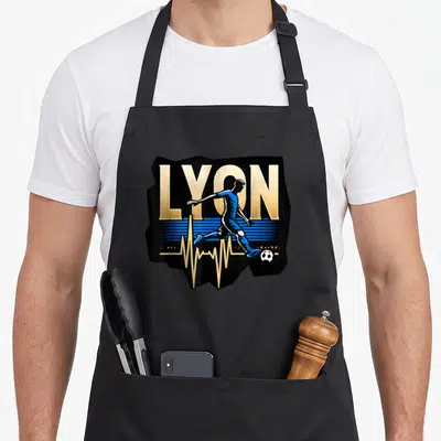 Tablier de cuisine noir avec inscription LYOR dorée, silhouette footballeur bleue et ligne de rythme cardiaque stylisée.