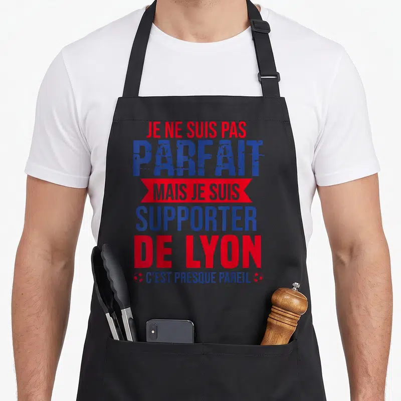 Tablier de cuisine noir avec le texte Je ne suis pas parfait mais je suis supporter de Lyon en bleu et rouge.