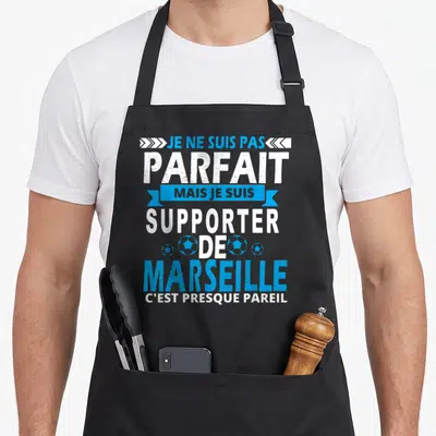 Tablier de cuisine noir avec le texte blanc et bleu Je ne suis pas parfait supporter de Marseille illustré par des ballons de foot.
