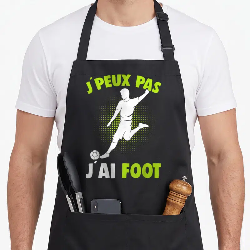 Tablier de cuisine noir avec silhouette blanche de joueur de foot et texte vert lime J'peux pas j'ai foot