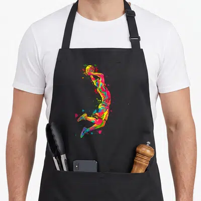 Tablier de cuisine noir avec illustration d'un basketteur en plein saut, peint en couleurs vives et éclaboussures artistiques dynamiques.