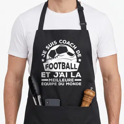 Tablier de cuisine noir avec illustration blanche d'une bottine de foot et le texte Je suis coach de football et j'ai la meilleure équipe du monde.