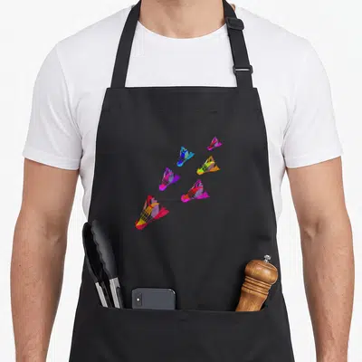 Tablier de cuisine noir avec six volants badminton multicolores en mouvement sur le devant.