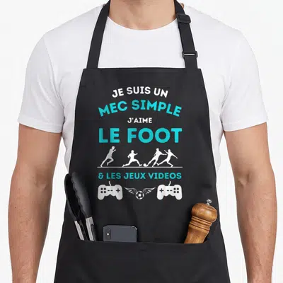 Tablier de cuisine noir avec inscription Je suis un mec simple le foot et les jeux videos, silhouettes de joueurs et manettes de console.