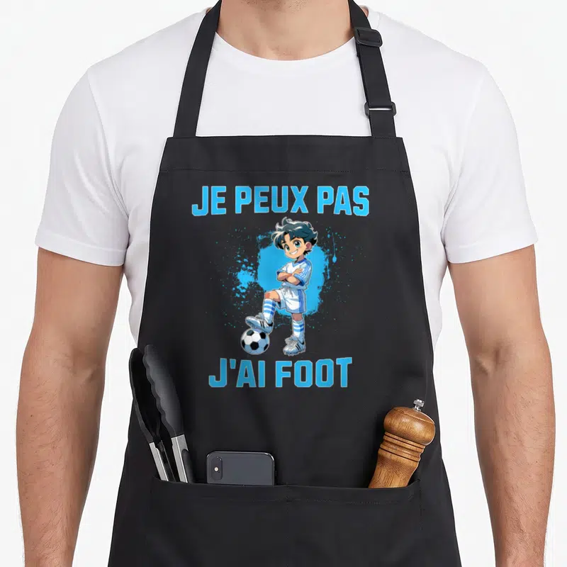 Tablier de cuisine noir avec un garçon manga en tenue de foot et le texte Je peux pas j'ai foot en bleu.