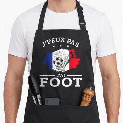 Tablier de cuisine noir avec inscription Je peux pas j'ai foot et illustration de botte de foot sur fond tricolore.