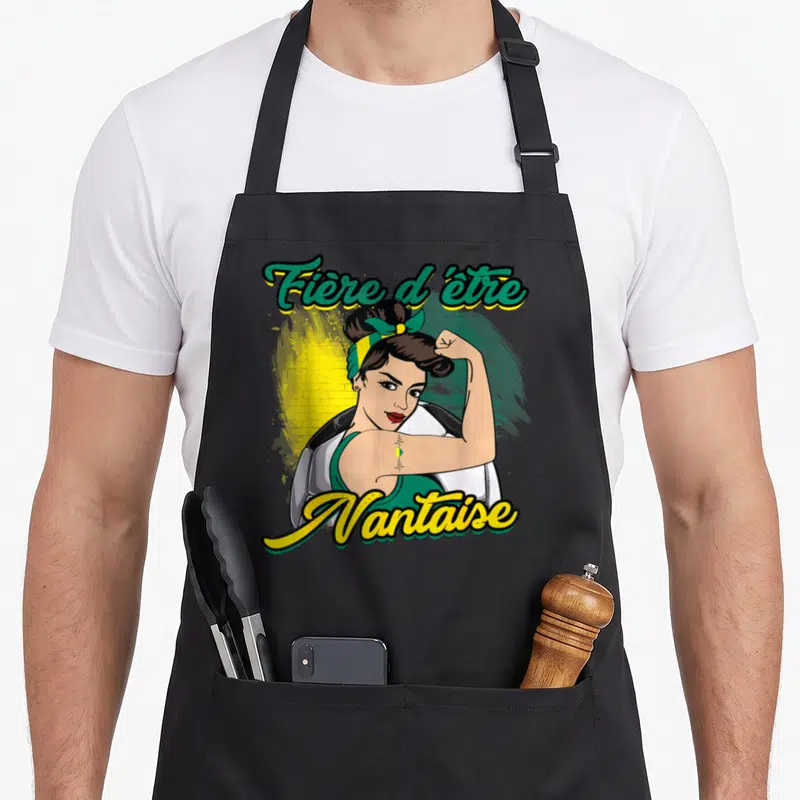 Tablier de cuisine noir avec illustration d'une femme musclée tenant un ballon de foot et le texte Fière d'être Nantaise.