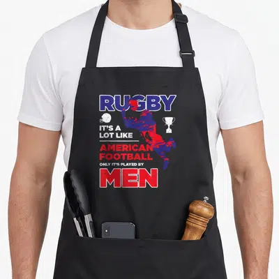 Tablier de cuisine noir avec illustration d'un joueur de rugby et texte humoristique en bleu et rouge.