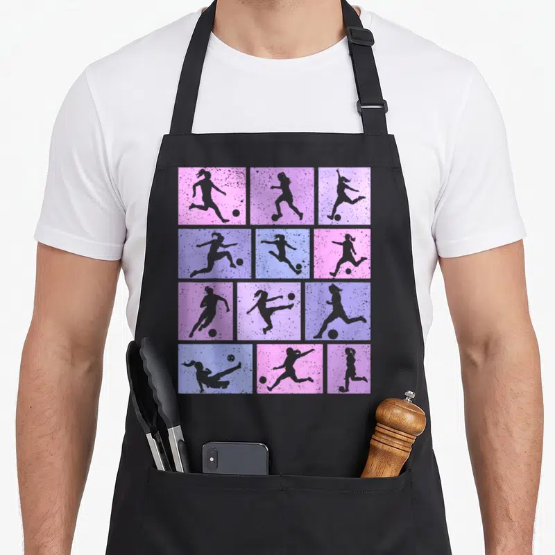 Tablier de cuisine noir avec motifs de joueuses de foot sur fonds roses et bleus pastels.