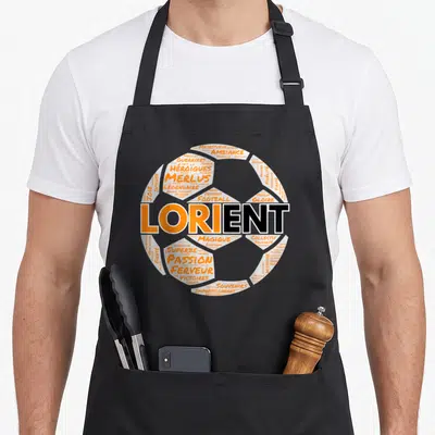 Tablier de cuisine noir avec un motif typographique en forme de ballon de football orange et blanc portant le mot Lorient au centre.