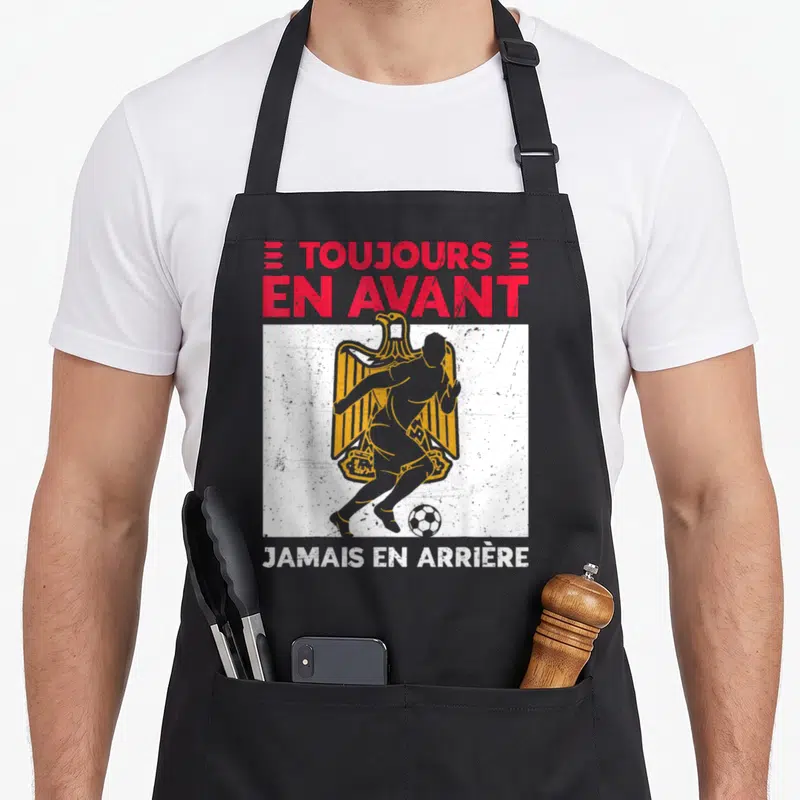 Tablier de cuisine noir avec inscription toujours en avant jamais en arrière et silhouette de footballeur sur aigle égyptien doré.