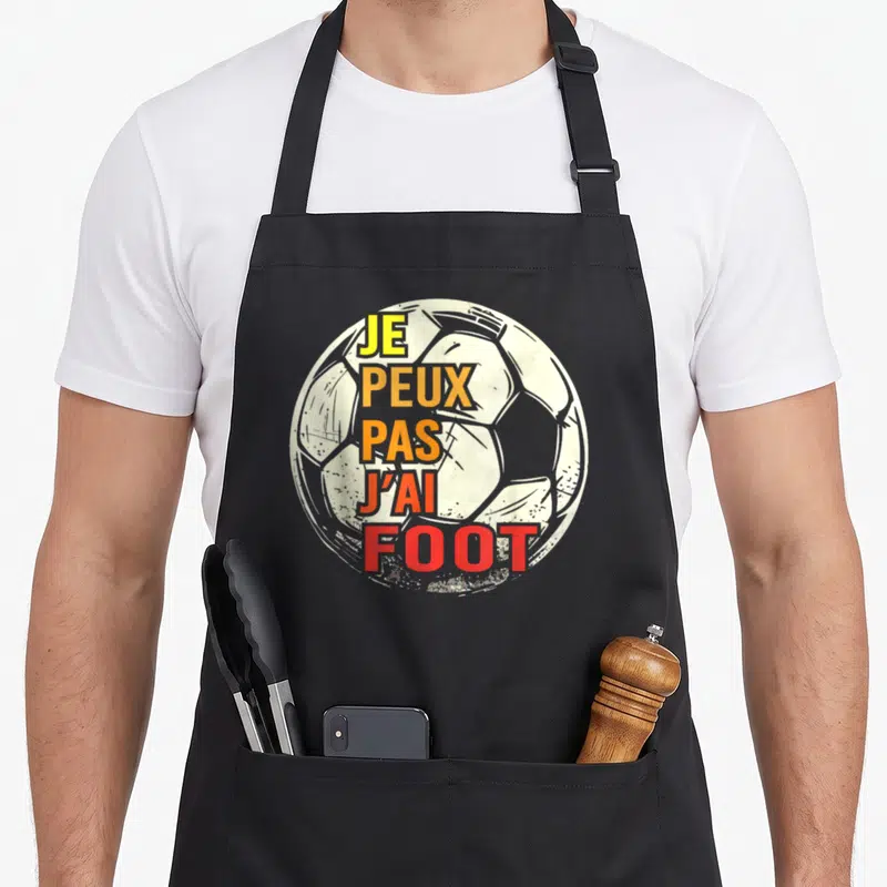 Tablier de cuisine noir avec un ballon de football blanc et le texte Je peux pas j'ai foot en lettres colorées.