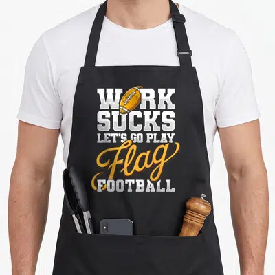 Tablier de cuisine noir avec message Work Sucks Let's Go Play Flag et illustration de ballon de football américain.