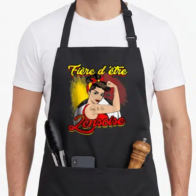 Tablier de cuisine noir avec illustration rétro d'une femme musclée et le texte Fière d'être Lenoise en lettres colorées.