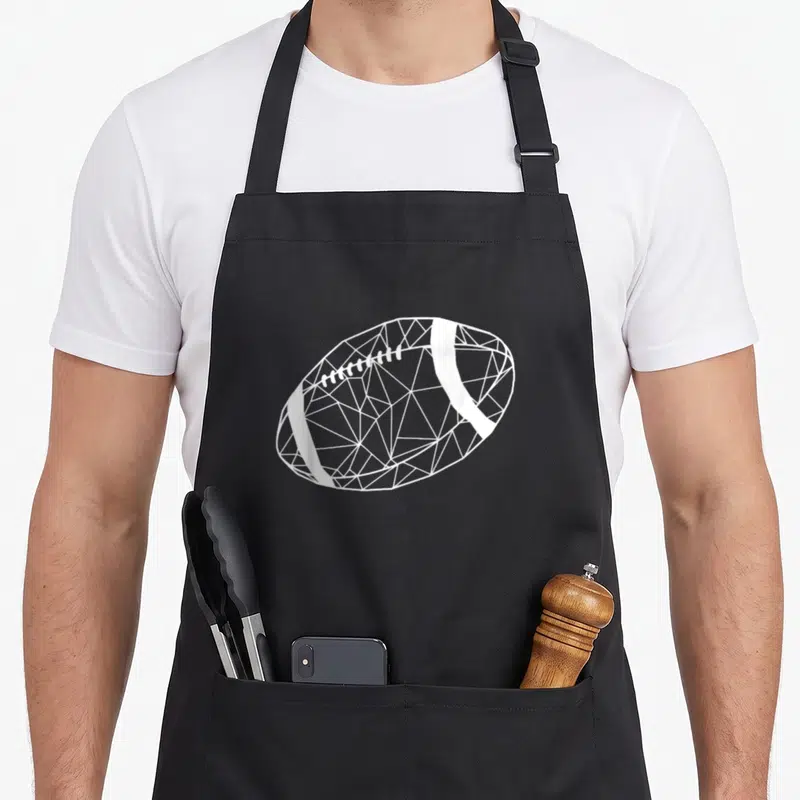 Tablier de cuisine noir avec un ballon de rugby dessiné en lignes blanches formant un motif géométrique triangulaire.