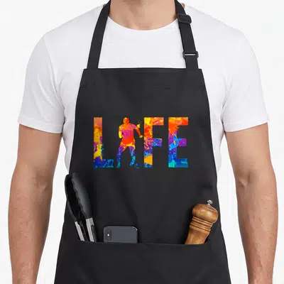 Tablier de cuisine noir avec motif LIFE et joueur de soccer aux couleurs vives et marbrées.
