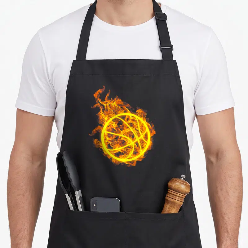 Tablier de cuisine noir avec illustration d'un ballon de basket balle entouré de flammes oranges et jaunes vives.