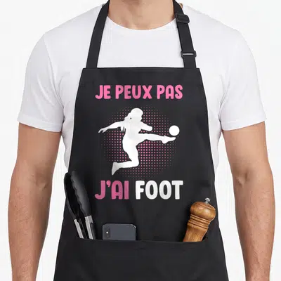 Tablier de cuisine noir avec silhouette femme jouant au foot et texte rose blanc