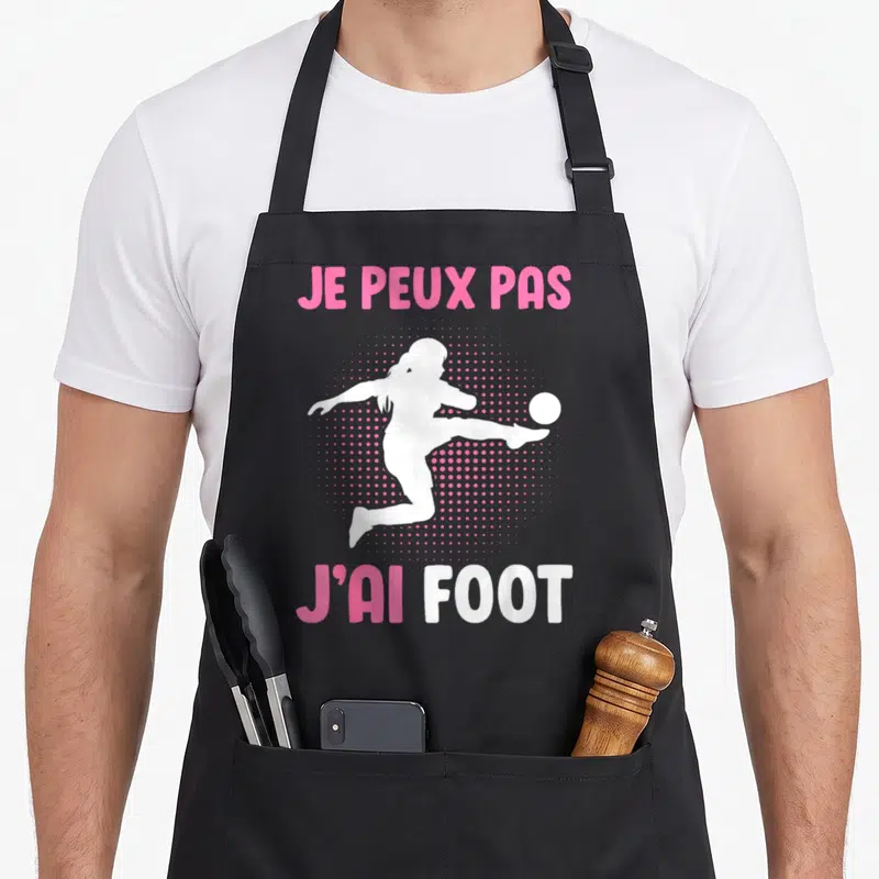 Tablier de cuisine noir avec silhouette femme jouant au foot et texte rose blanc