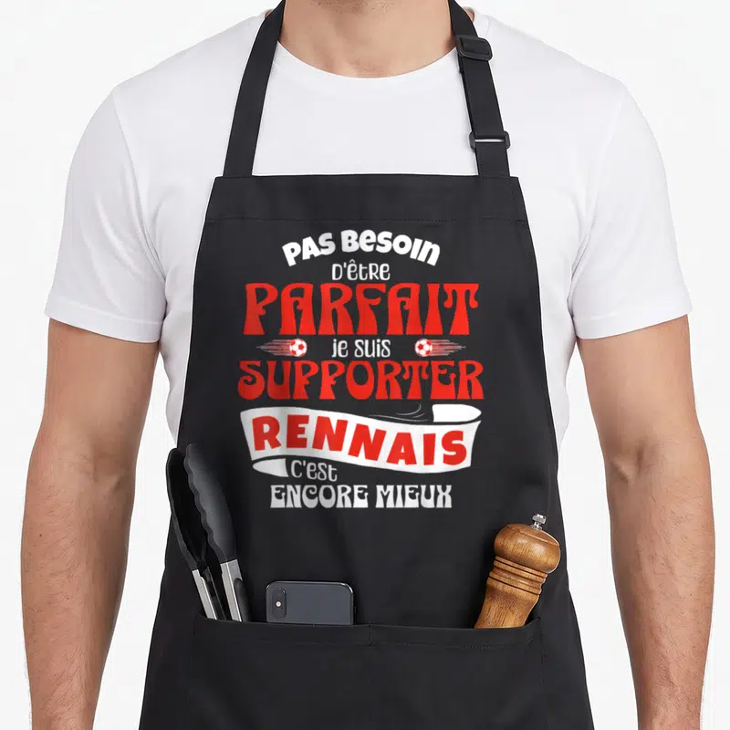 Tablier de cuisine noir avec le texte Pas Besoin d'être Parfait je suis Supporter Rennais c'est Encore Mieux en rouge et blanc.