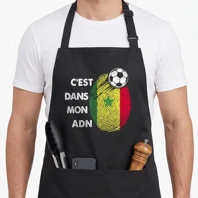 Tablier de cuisine noir avec une empreinte digitale aux couleurs du drapeau sénégalais et un ballon de football blanc en haut à droite.