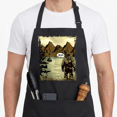 Tablier de cuisine noir avec une illustration de Bigfoot disant Bruh face au monstre du Loch Ness.