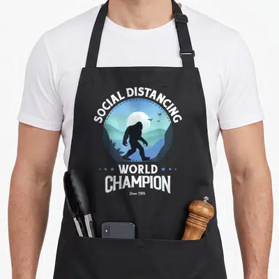 Tablier de cuisine noir avec illustration circulaire d'un Bigfoot et texte blanc Social Distancing World Champion Since 1984.
