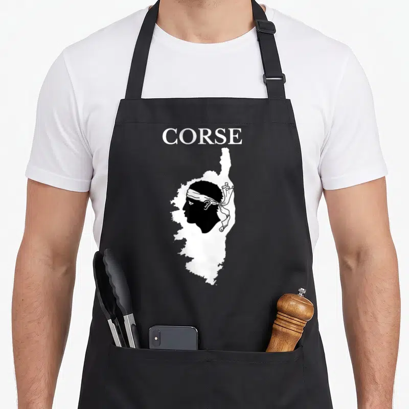 Tablier de cuisine noir avec une carte blanche de la Corse contenant un profil corse coiffé d'un bandana blanc.