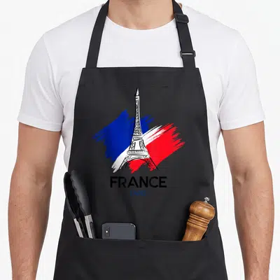 Tablier de cuisine noir avec une illustration de la Tour Eiffel sur des taches de peinture bleue, blanche et rouge.