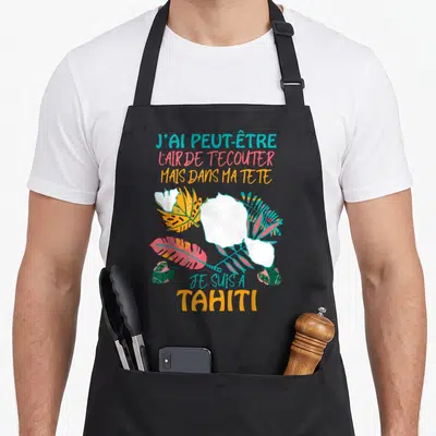 Tablier de cuisine noir avec inscription colorée et feuilles tropicales stylisées sur le devant.