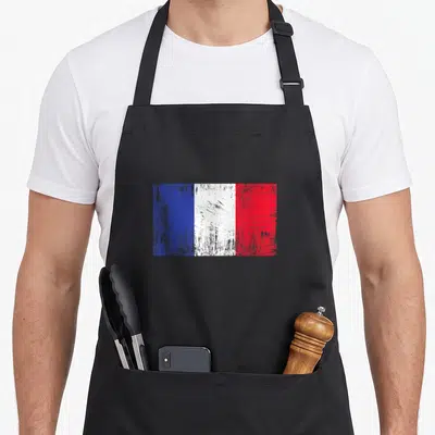 Tablier de cuisine noir avec un drapeau français vintage aux couleurs bleue, blanche et rouge texturées.