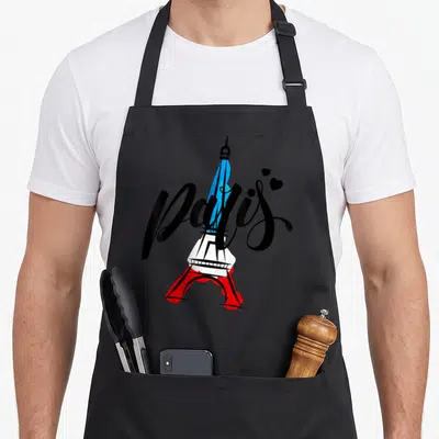 Tablier de cuisine noir avec une illustration colorée de la Tour Eiffel et l'inscription Paris en lettres noires stylisées.