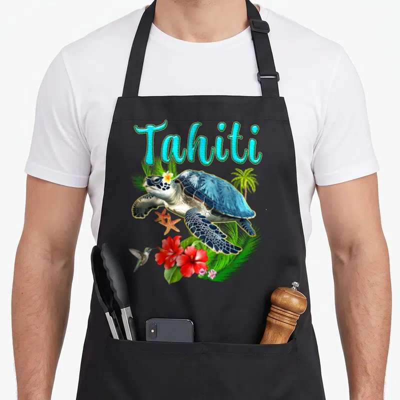 Tablier de cuisine noir avec illustration d'une tortue, d'un colibri, de fleurs rouges et du mot Tahiti en lettres turquoise.