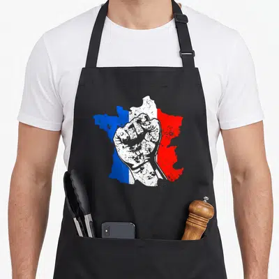 Tablier de cuisine noir avec une carte de France aux couleurs du drapeau et un poing levé blanc au centre.